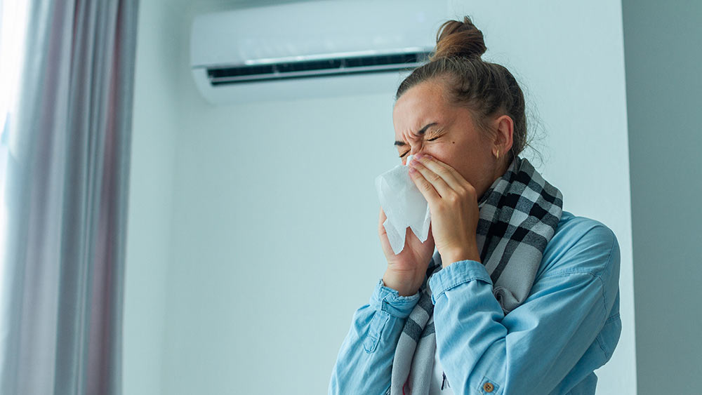 Mujer estornuda porque el crecimiento de moho en su aire acondicionado está agravando sus problemas de alergia