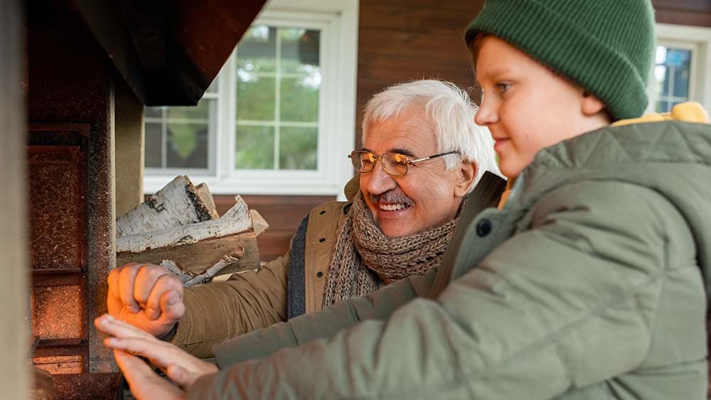 Un anciano y su nieto se calientan las manos frente a un calentador casero